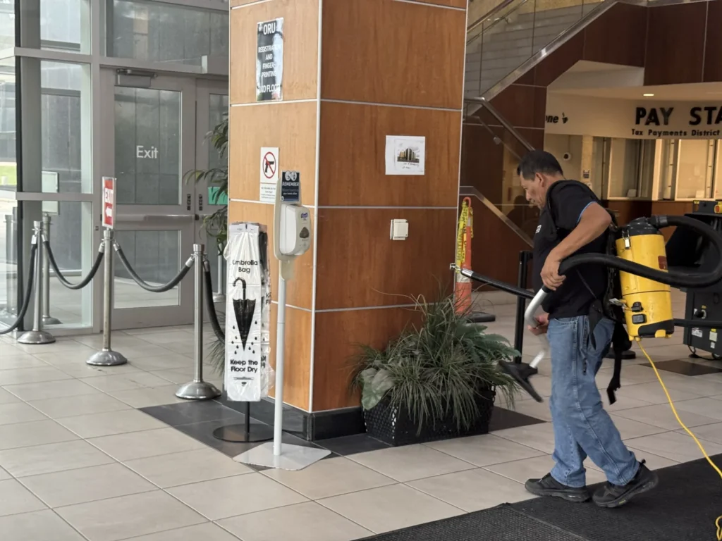 Cleaner using a backpack vacuum in a building lobby