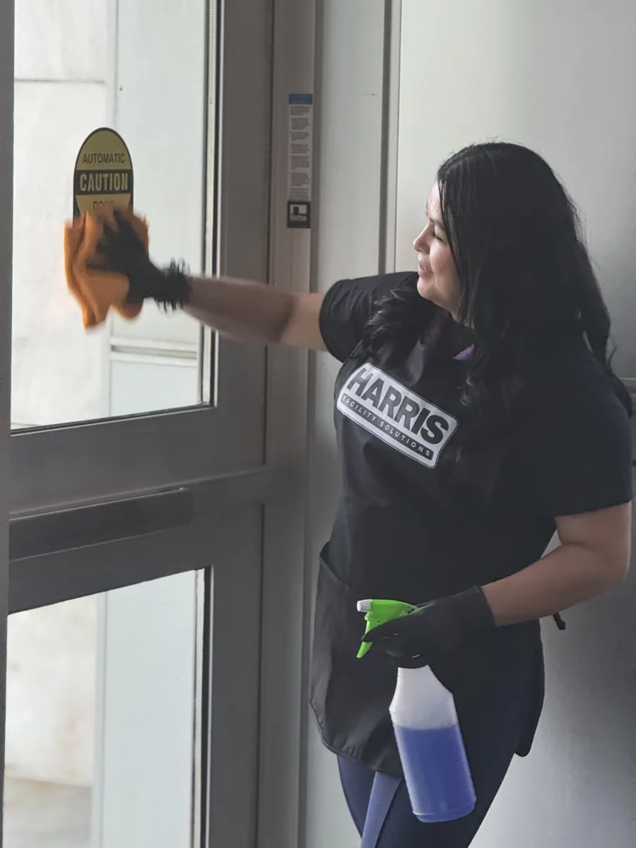 Harris team member wiping a glass entrance door